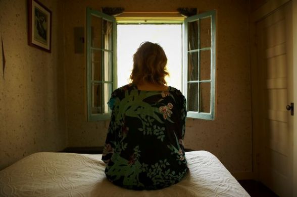 Woman-sitting-on-bed-looking-out-window